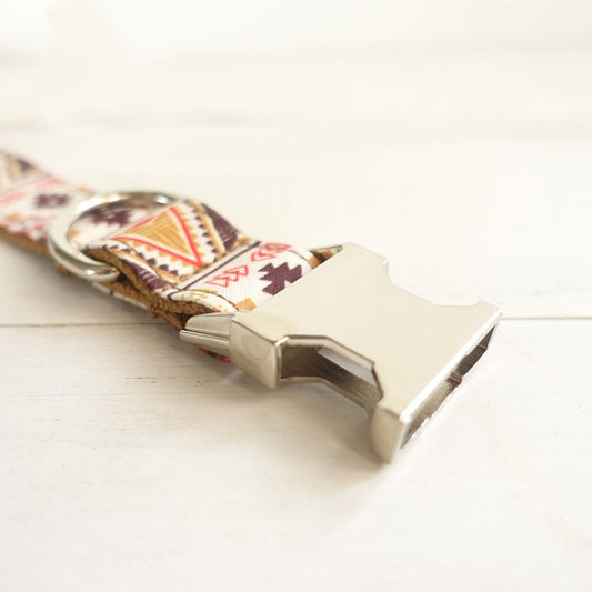 Dog collar with patterned design and metallic clasp on a light background