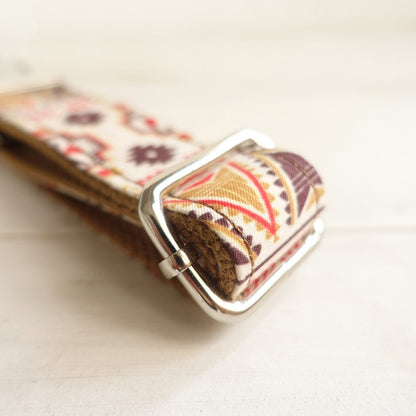 Close-up of a belt with a floral pattern and silver buckle on a light background