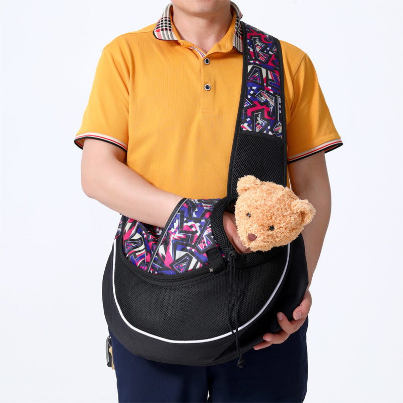 Person holding a black and purple pet carrier with a teddy bear inside, against a white background